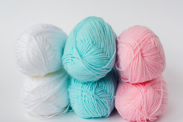 acrylic soft pastel pink, azure and white colored wool yarn thread skeins row on white background,...