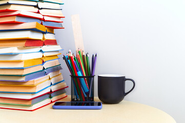 Educational background. Books piles pencils cup and smartphone on table over white background for copy space
