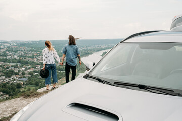 Fototapeta premium Young Trendy Traveling Couple Having Fun Near the Car on Top of Hill, Travel and Road Trip Concept