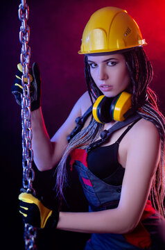 a construction girl in a hard hat and overalls with a long chain in her hands