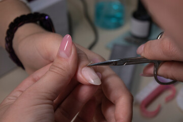 the process of doing manicure. Closeup of hands of professional manicurist, removing cuticle in salon. Concept of doing manicure and fingernails cleaning. beauty concept. Gel polish, shellac