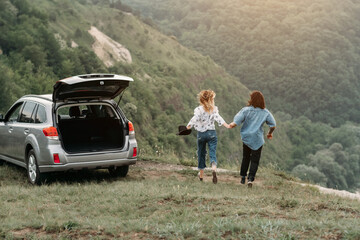 Young Trendy Traveling Couple Having Fun Near the Car on Top of Hill, Travel and Road Trip Concept