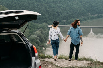 Young Trendy Traveling Couple Having Fun Near the Car on Top of Hill, Travel and Road Trip Concept