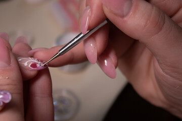 the process of doing manicure. Closeup of hands of professional manicurist, applying little stones on nails. Concept of doing manicure. beauty concept. Gel polish, shellac