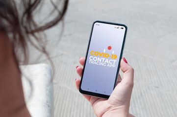 Woman using a covid-19 tracking app outdoor to prevent contagion from coronavirus