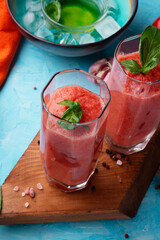  classic spanish raw eating cold soup Gazpacho served  in glasses around blue background. food recipe. healthy concept.