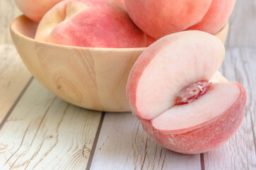 Fresh organic peach or apricot in wood bowl on wood background.