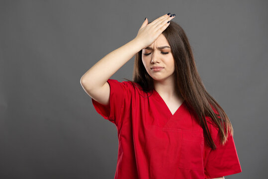 Young Nurse Wearing Red Scrubs Has A Headache