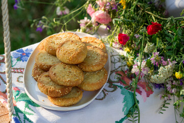 Obraz na płótnie Canvas Shortbread cookies with blue cheese and sesame seeds and a wreath of wildflowers on a swing. Rustic style.