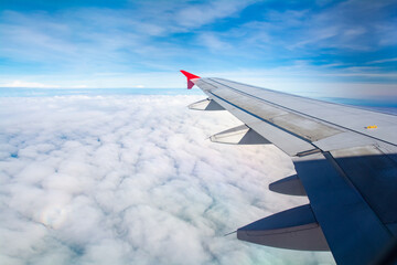 Obraz premium Wing of an airplane flying above the morning clouds, copy space for text.