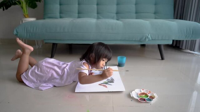 little girl is painting using watercolors in the living room