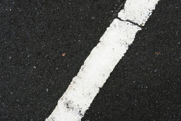 Color of white traffic lines with cracks on wet asphalt road.