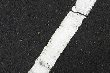 Fototapeta premium Color of white traffic lines with cracks on wet asphalt road.
