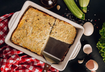Zucchini casserole on dark background. Dietary, low-calorie, healthy food. Homemade Casserole from squash with chicken and eggs. Top view