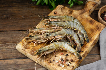 Tiger prawns on a wooden serving Board on a brown wooden table. Lots of tiger prawns close up