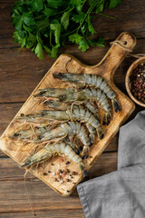 Tiger prawns on a wooden serving Board on a brown wooden table. Lots of tiger prawns close up