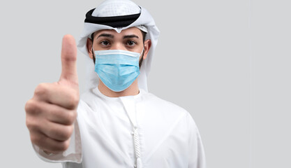 Young man in sterile face mask posing in grey background. Epidemic pandemic rapidly spreading coronavirus covid-19 flu virus concept. Showing thumbs up