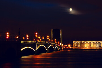 A bridge lit by lights on a moonlit night. The bridge on the Neva River in St. Petersburg.