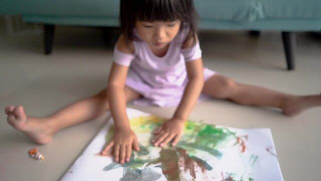 little girl was painting in a drawing book using both hands
