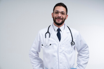 Fototapeta premium Portrait of a happy young male doctor in white uniform with stethoscope standing on white background. The concept of health and prevention.
