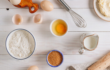 Ingredients for baking and Breakfast with eggs, flour, sugar, milk and butter on a white wooden background. Delicious and healthy food. Flat lay. Top view