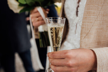 A glass of champagne in the hands of a guest at a wedding