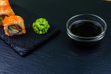 Sushi roll philadelphia with salmon, rice, cheese, cucumber, avocado and caviar on a slate board. Japanese food