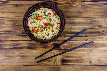 Instant noodle with shrimps, red pepper and green onion in a ceramic bowl. Japanese food. Top view