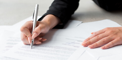 Woman's hand with pen signing document, close up