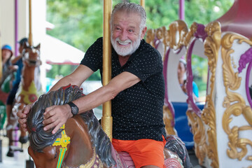 Caucasian Senior man smile on carousel at the amusement park