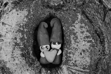Two loving dwarfs made of plasticine on a wooden background.