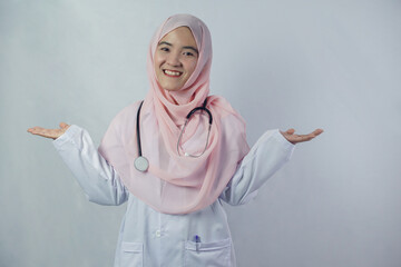 Portrait of friendly, smiling confident Muslim female doctor in hijab dress holding a stethoscope on white background. She looking at camera and stretching both arms out to the side of the body