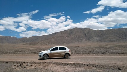 Car positioned in front of the mountains in the desert  - obrazy, fototapety, plakaty