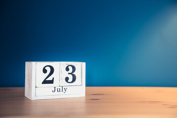 July 23 - white calendar blocks on wooden table against vintage blue background