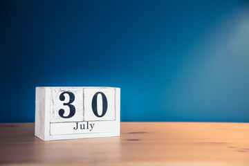 July 30 - white calendar blocks on wooden table against vintage blue background