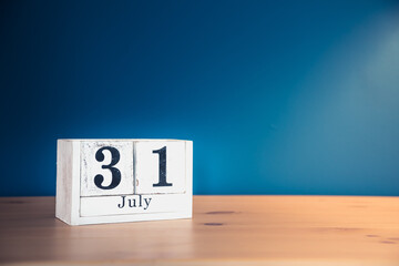 July 31 - white calendar blocks on wooden table against vintage blue background