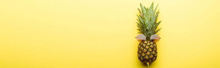 top view of ripe pineapple in sunglasses on yellow background, panoramic shot