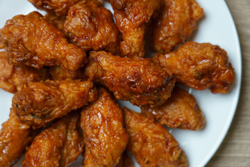 Plate of spicy deep fried chicken wings, Korean food style on wooden table.