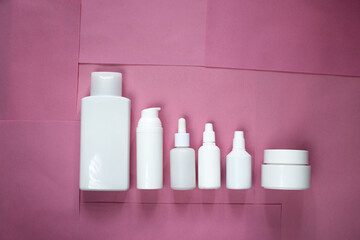 Simple Blank white Plastic Bottles Set.set of cosmetic products on a pink blue background. Cosmetic package collection for cream, soups, foams, shampoo.Mock up white cosmetic bottles with palm leaf.