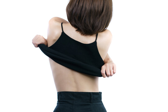 woman taking off her black shirt, back view. White background.