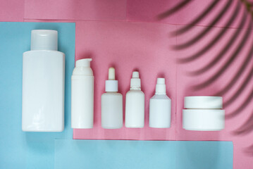 Simple Blank white Plastic Bottles Set.set of cosmetic products on a pink blue background. Cosmetic package collection for cream, soups, foams, shampoo.Mock up white cosmetic bottles with palm leaf.