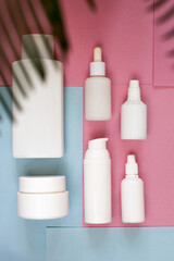 Simple Blank white Plastic Bottles Set.set of cosmetic products on a pink blue background. Cosmetic package collection for cream, soups, foams, shampoo.Mock up white cosmetic bottles with palm leaf.