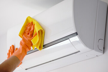 Asian man cleaning air conditioner with microfiber cloth