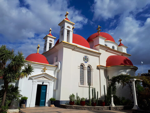 A beautiful temple of twelve apostles in Capernaum, on the shores of the Sea of Galilee. Horizontal photo of bible places, white clouds on a bright blue sky