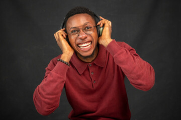young black man listening to music on his headphones, feeling excited