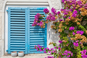 Fototapeta na wymiar Traditional mediterranean house with blue shutters and purple flowers