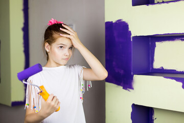 Repair in the apartment. Happy child girl paints the wall