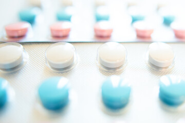 Blisters with round multi-colored tablets red yellow blue white light background close-up macro, antibiotics, vitamins, analgesic. Care, health.