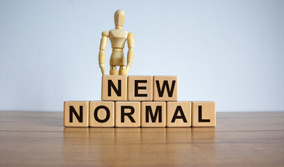 Concept words 'new normal' on cubes on a beautiful wooden table. Wooden model of human. Beautiful white background. Business concept.