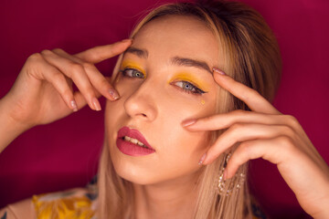 Obraz premium Girl with blond hair and yellow make-up on a pink background 